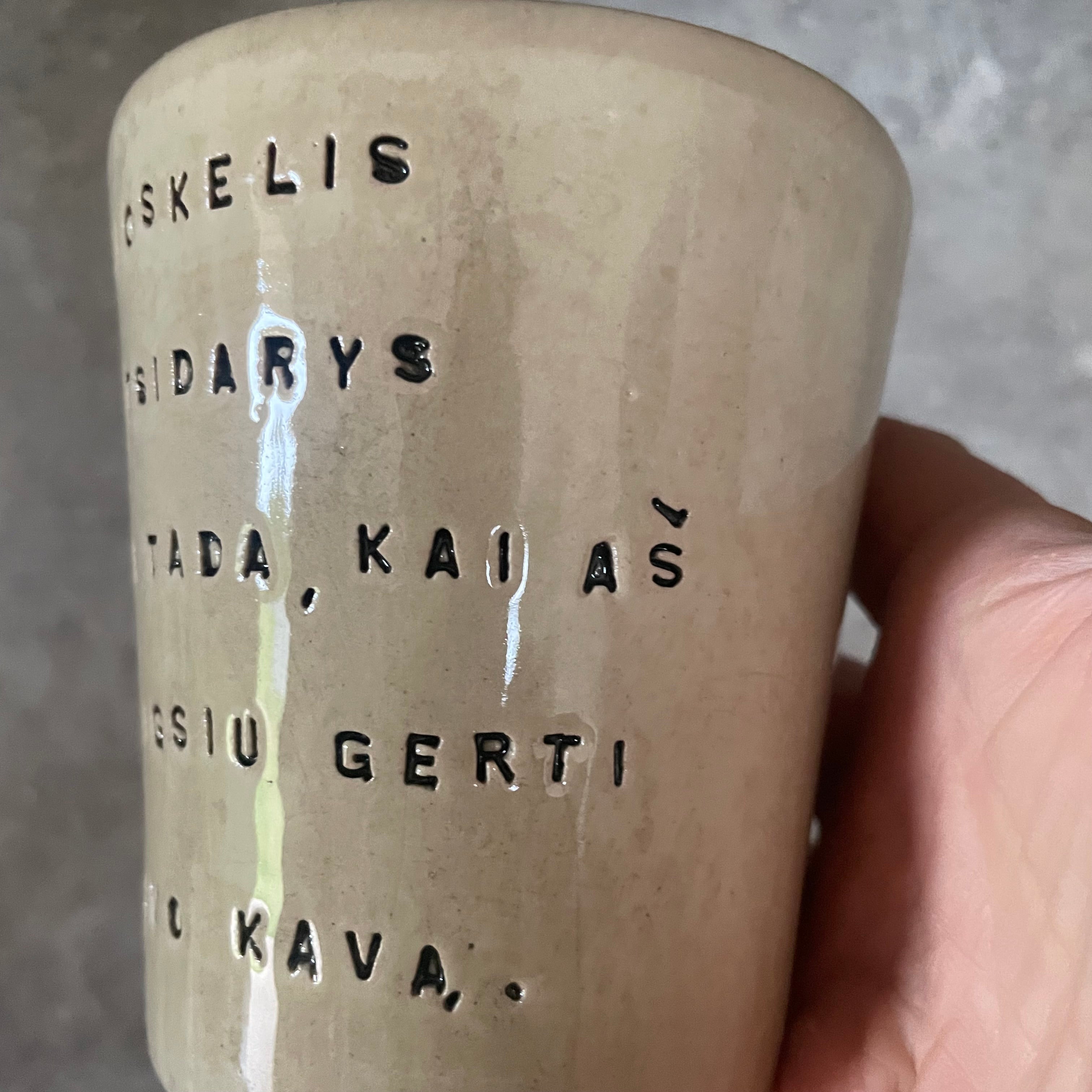 Puodelis su smagiu užrašu apie kavą ir kioskelį