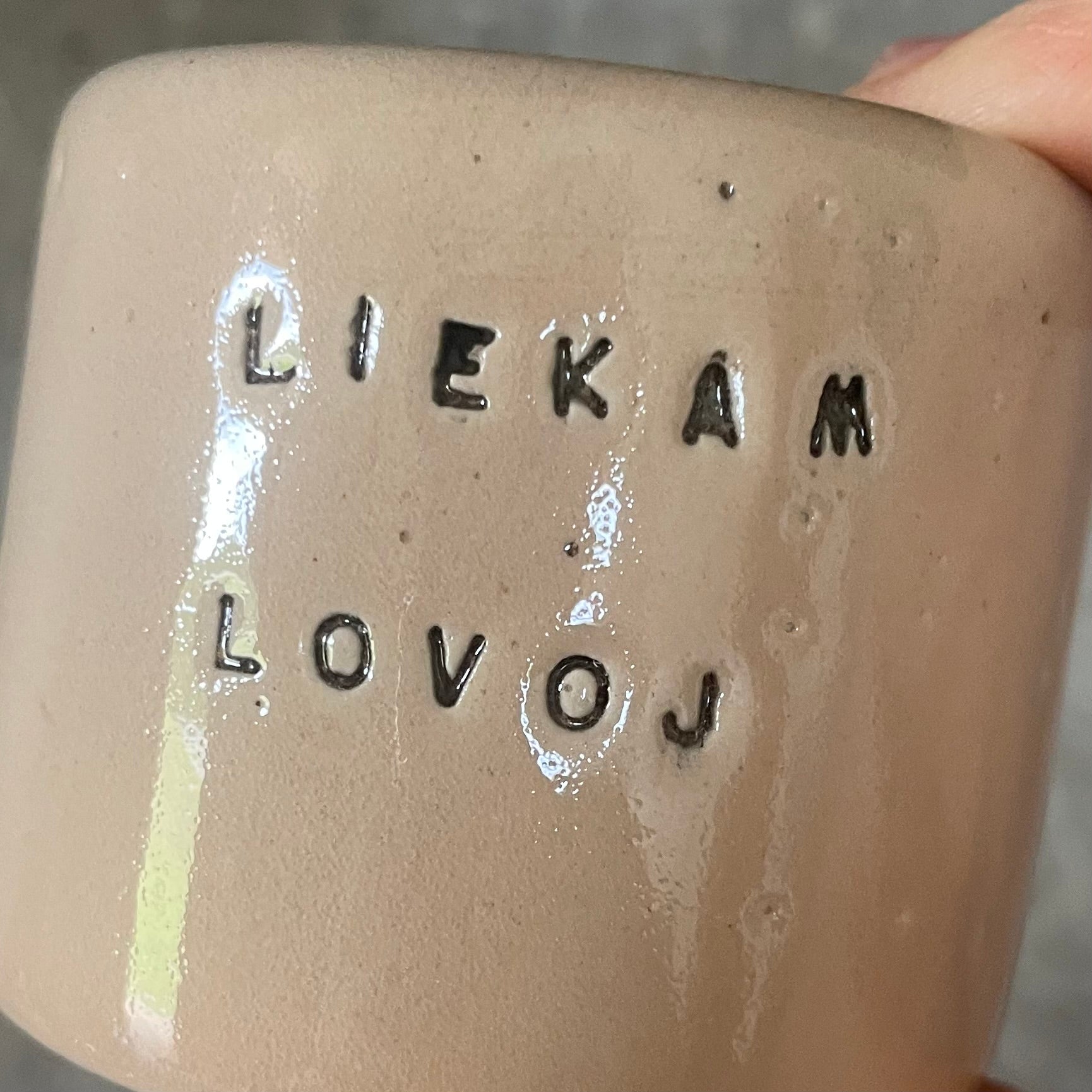 A pair of small mugs with words in Lithuanian