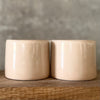 A pair of small mugs with words in Lithuanian