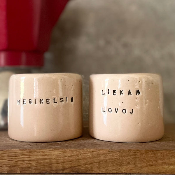 A pair of small mugs with words in Lithuanian