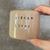 A pair of small mugs with words in Lithuanian