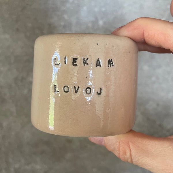A pair of small mugs with words in Lithuanian