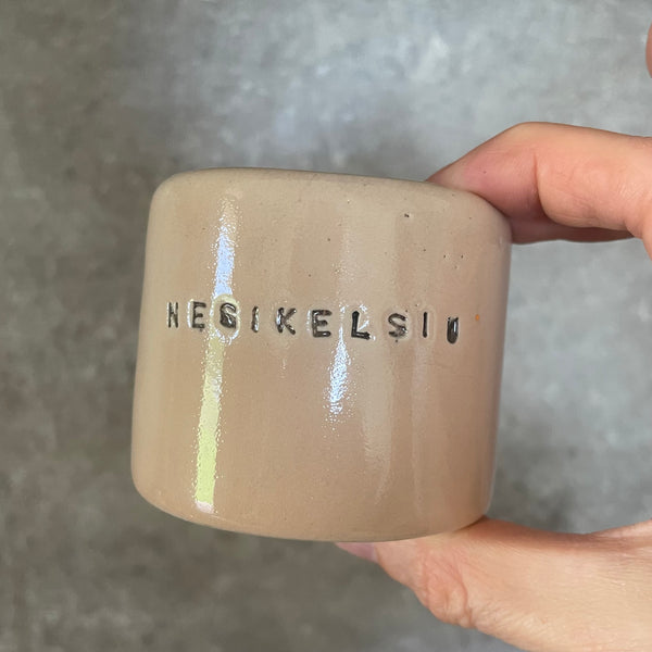A pair of small mugs with words in Lithuanian
