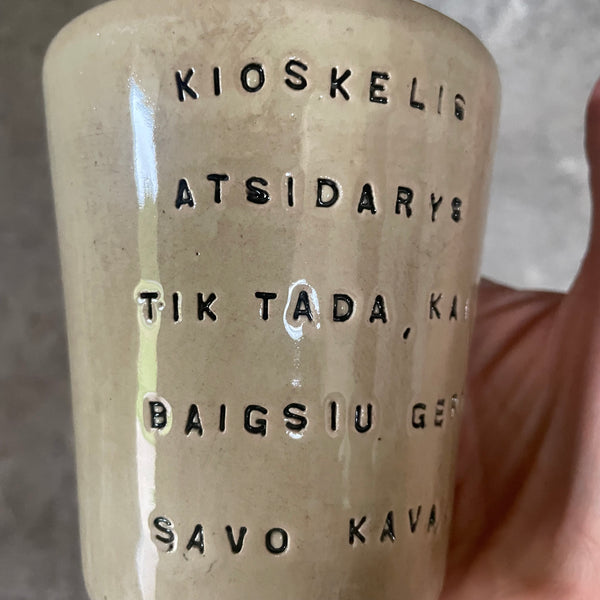 Puodelis su smagiu užrašu apie kavą ir kioskelį