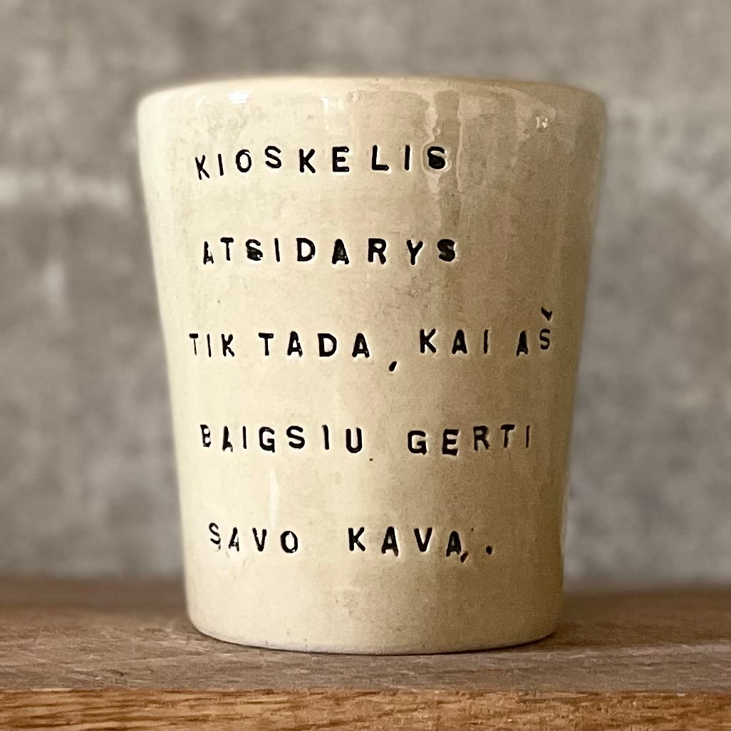 Puodelis su smagiu užrašu apie kavą ir kioskelį