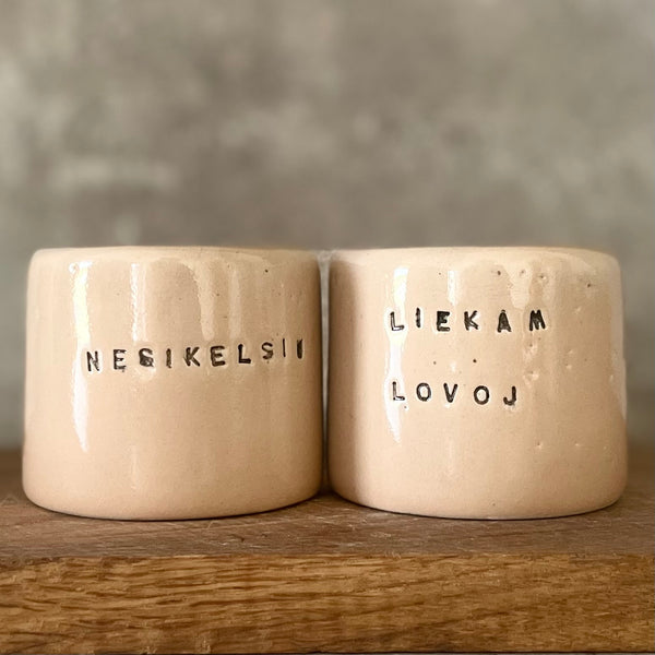 A pair of small mugs with words in Lithuanian