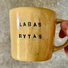Yellow cup with saying "LABAS RYTAS"