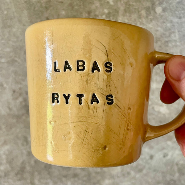 Yellow cup with saying "LABAS RYTAS"