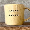 Yellow cup with saying "LABAS RYTAS"