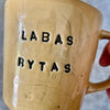 Yellow cup with saying "LABAS RYTAS"