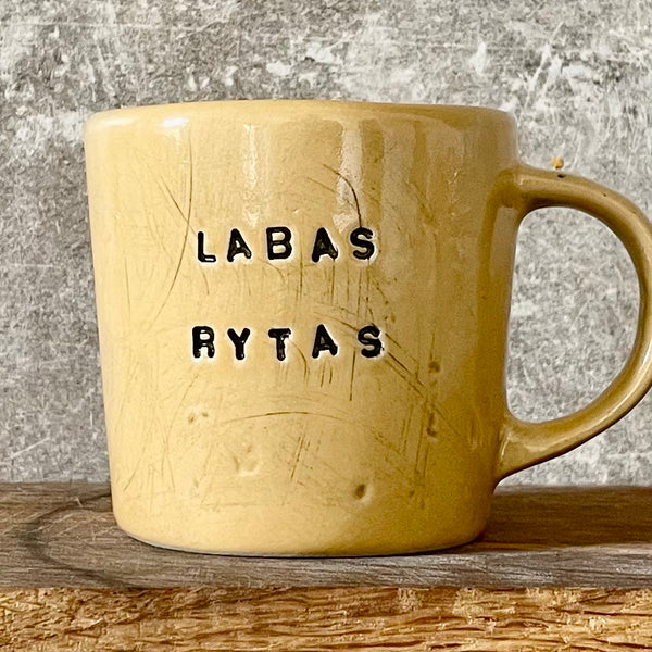 Yellow cup with saying "LABAS RYTAS"