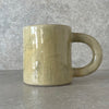 Yellow ceramic mug with saying about coffee