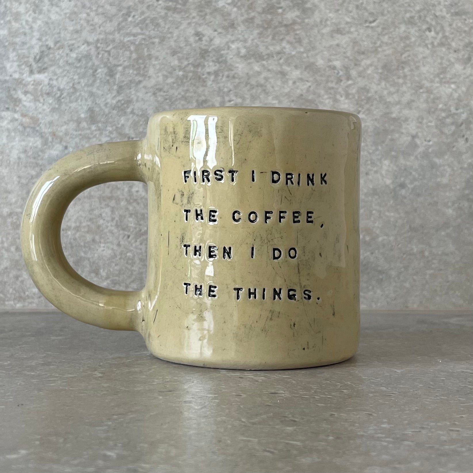Yellow ceramic mug with saying about coffee