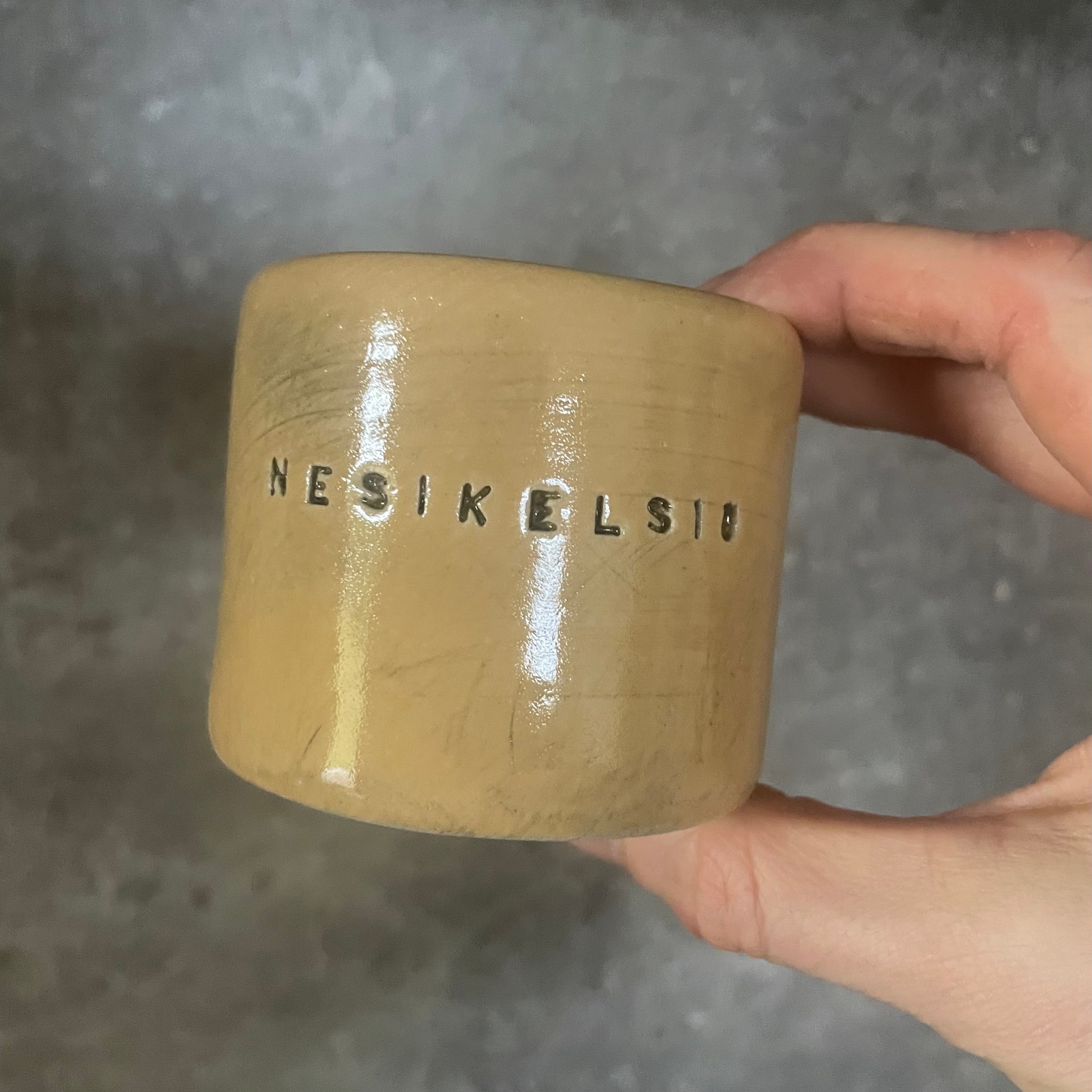 A pair of small mugs with words in Lithuanian