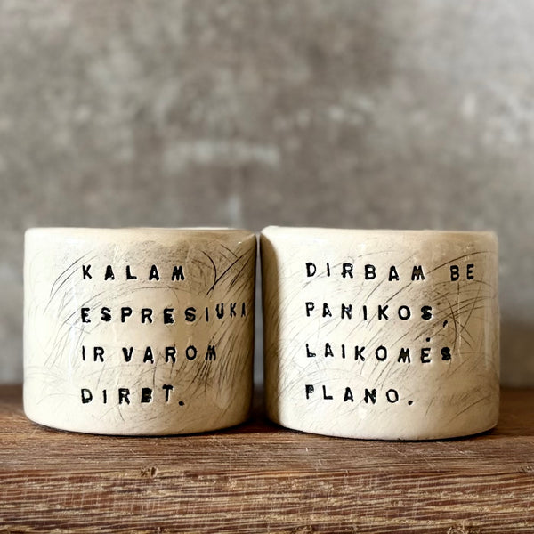 Du maži espresso puodeliai su tekstu apie darbą