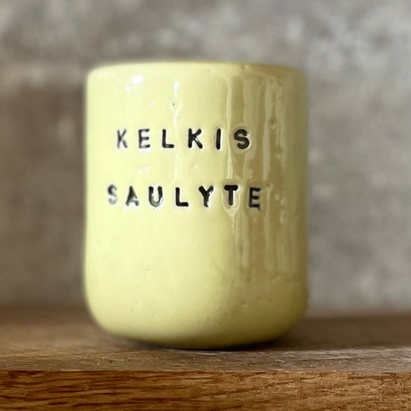 Small yellow tumbler mug with words in Lithuanian
