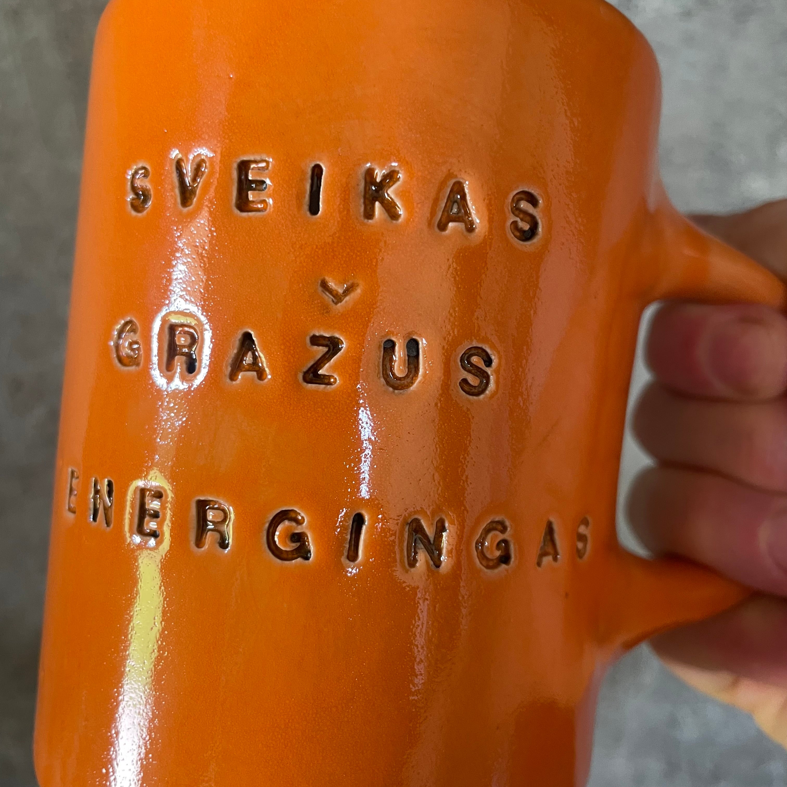 Oranžinis puodelis su afirmacija jam