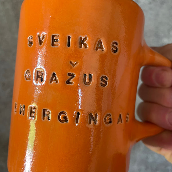 Oranžinis puodelis su afirmacija jam