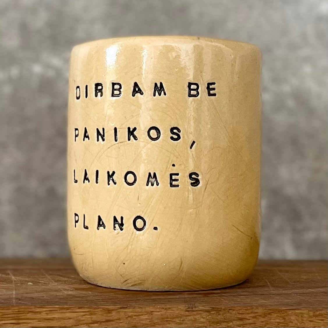 Geltonas didelis puodelis be rankenos su užrašu