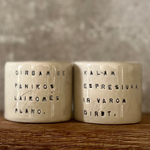 Du maži espresso puodeliai su tekstu apie darbą