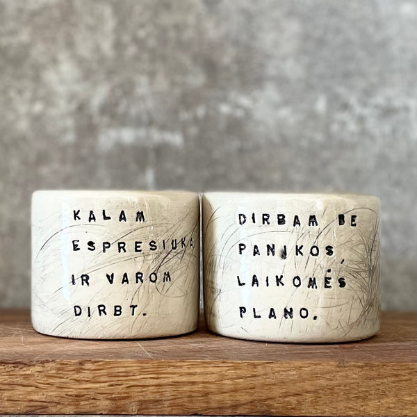 Du maži espresso puodeliai su tekstu apie darbą