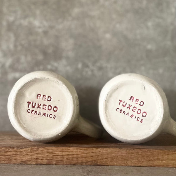 Two big ceramic mugs with words about work