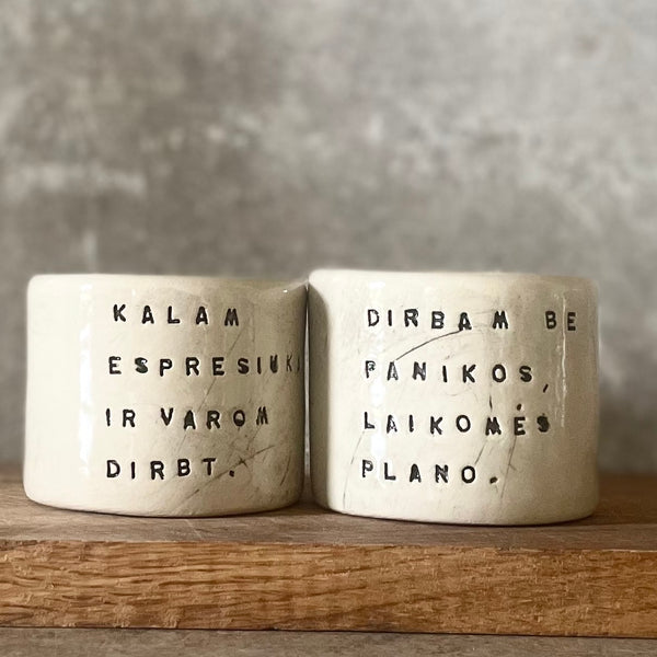 Du maži espresso puodeliai su tekstu apie darbą