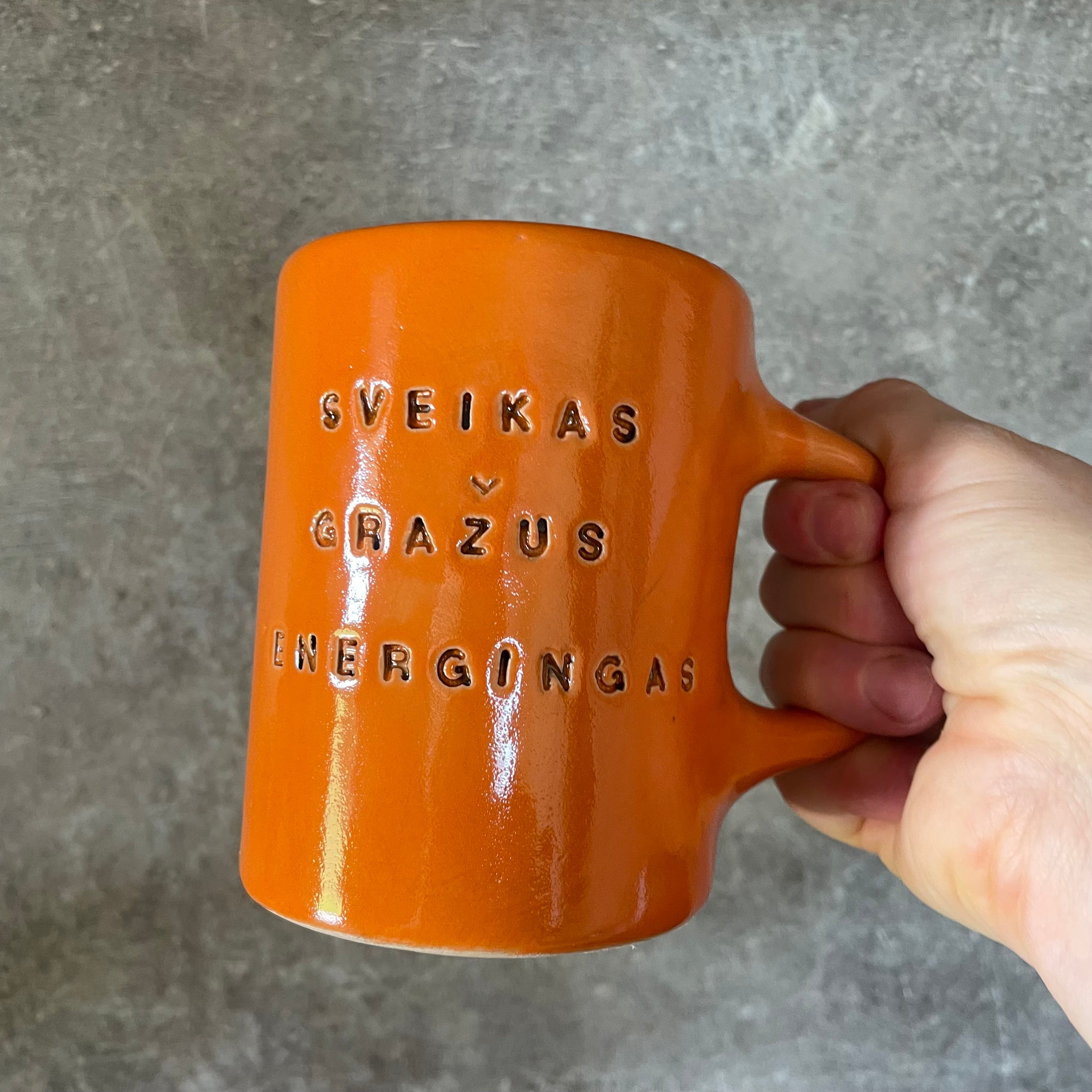 Oranžinis puodelis su afirmacija jam