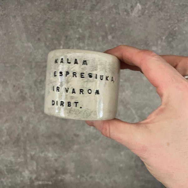 A set of small mugs with words in Lithuanian