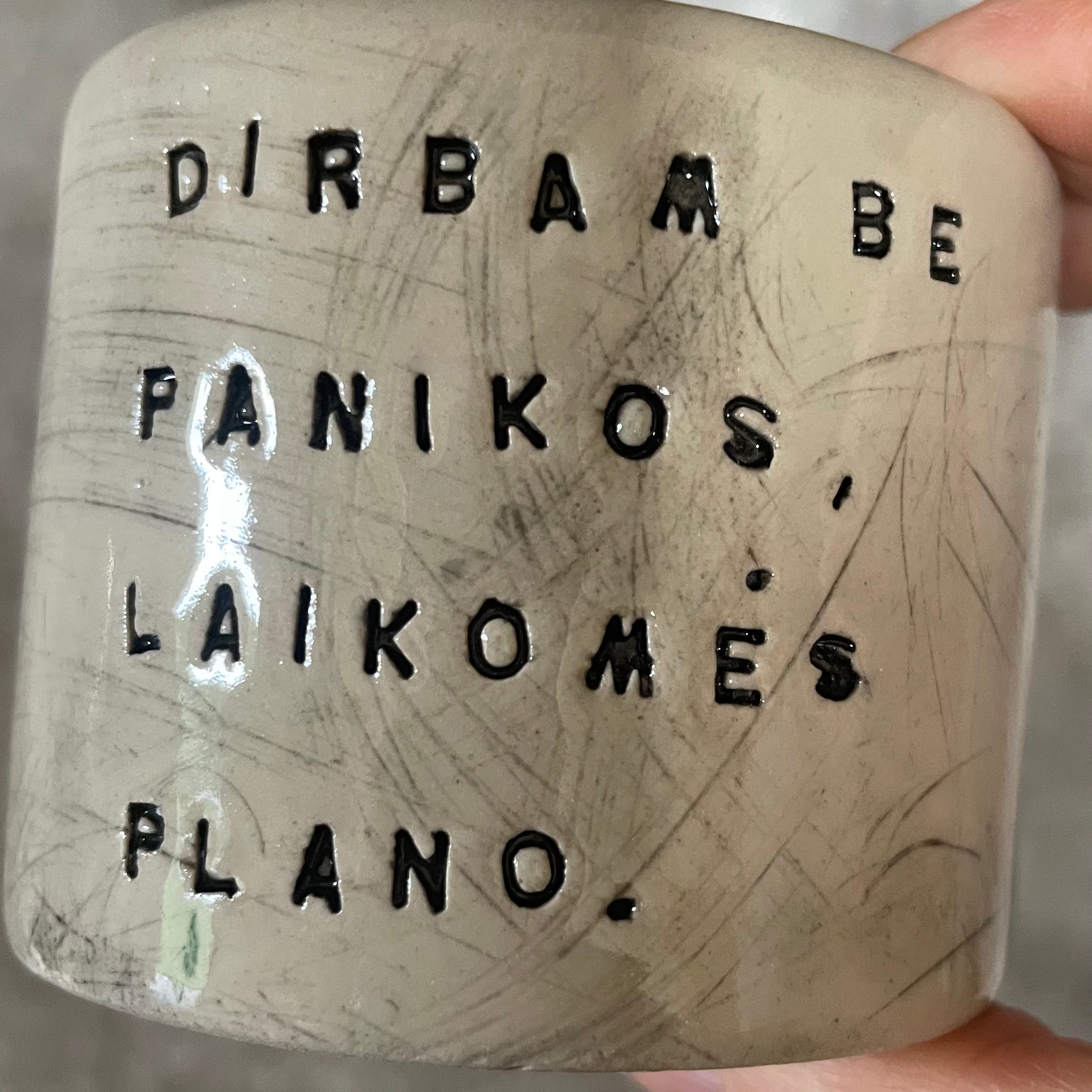A set of small mugs with words in Lithuanian