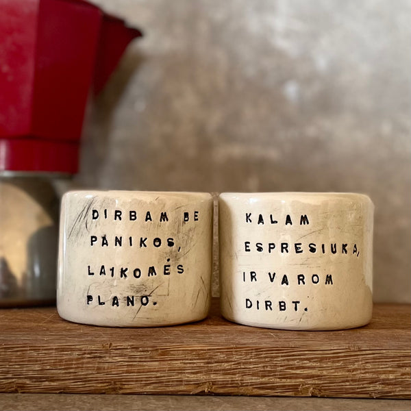 Du maži espresso puodeliai su tekstu apie darbą