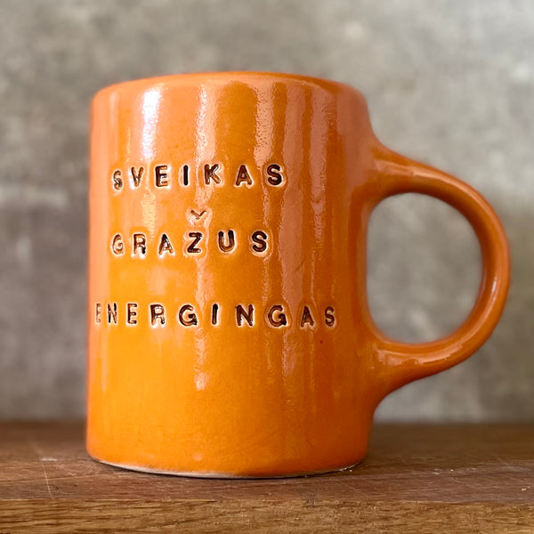 Oranžinis puodelis su afirmacija jam
