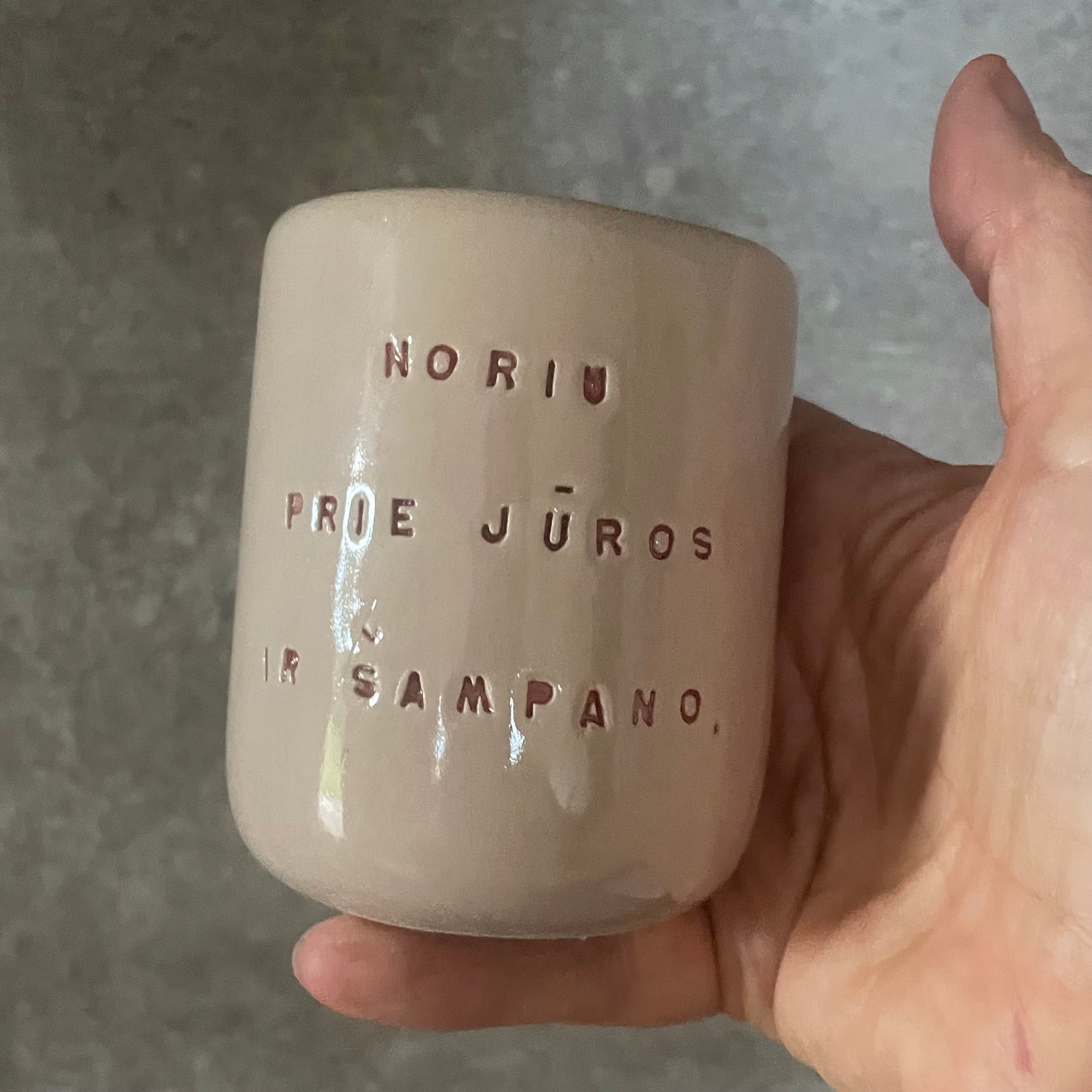 Small pink mug without handle with text in Lithuanian