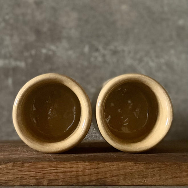 A pair of small mugs with words in Lithuanian