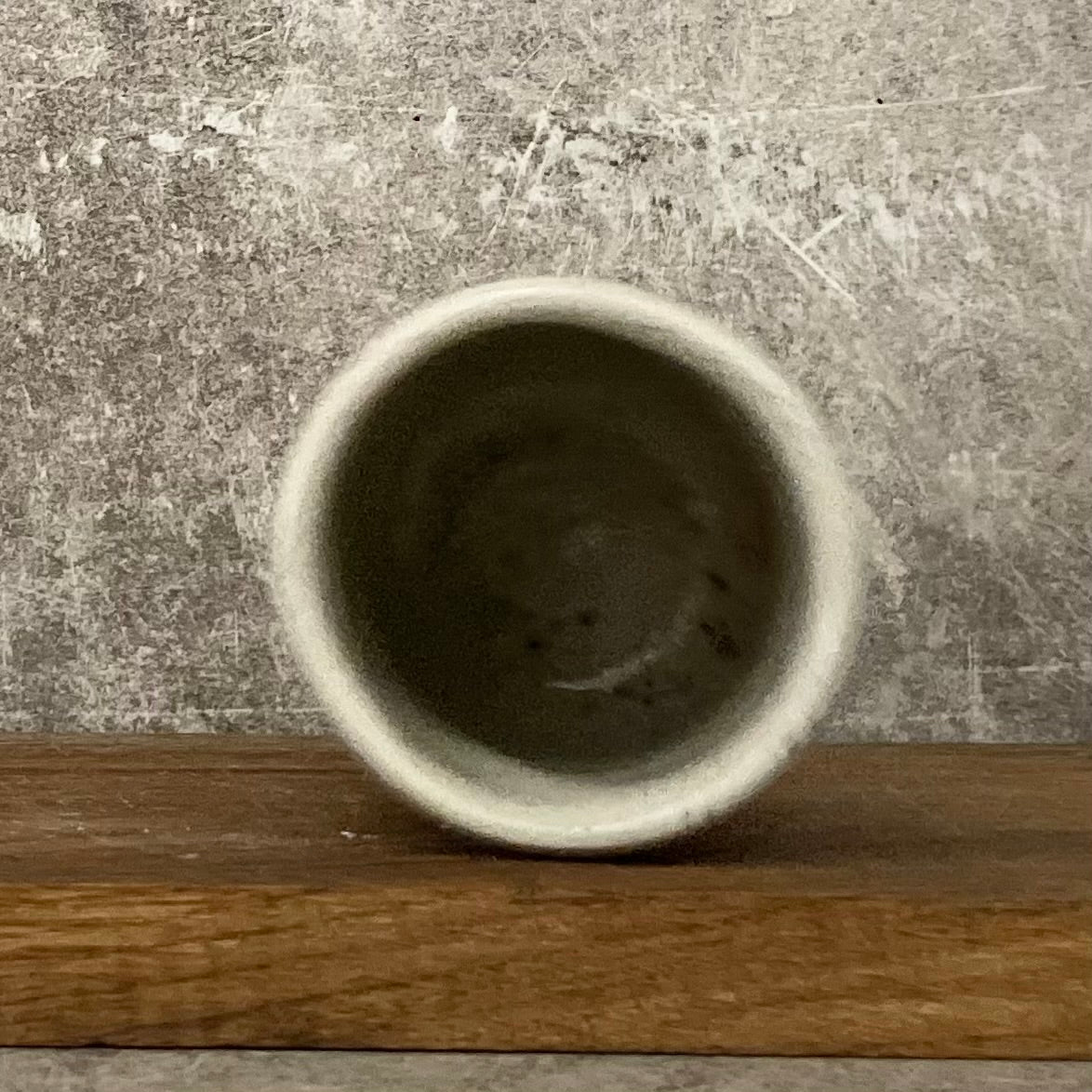 Small speckled mug without handle with text in Lithuanian