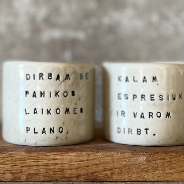 A set of small mugs with words in Lithuanian