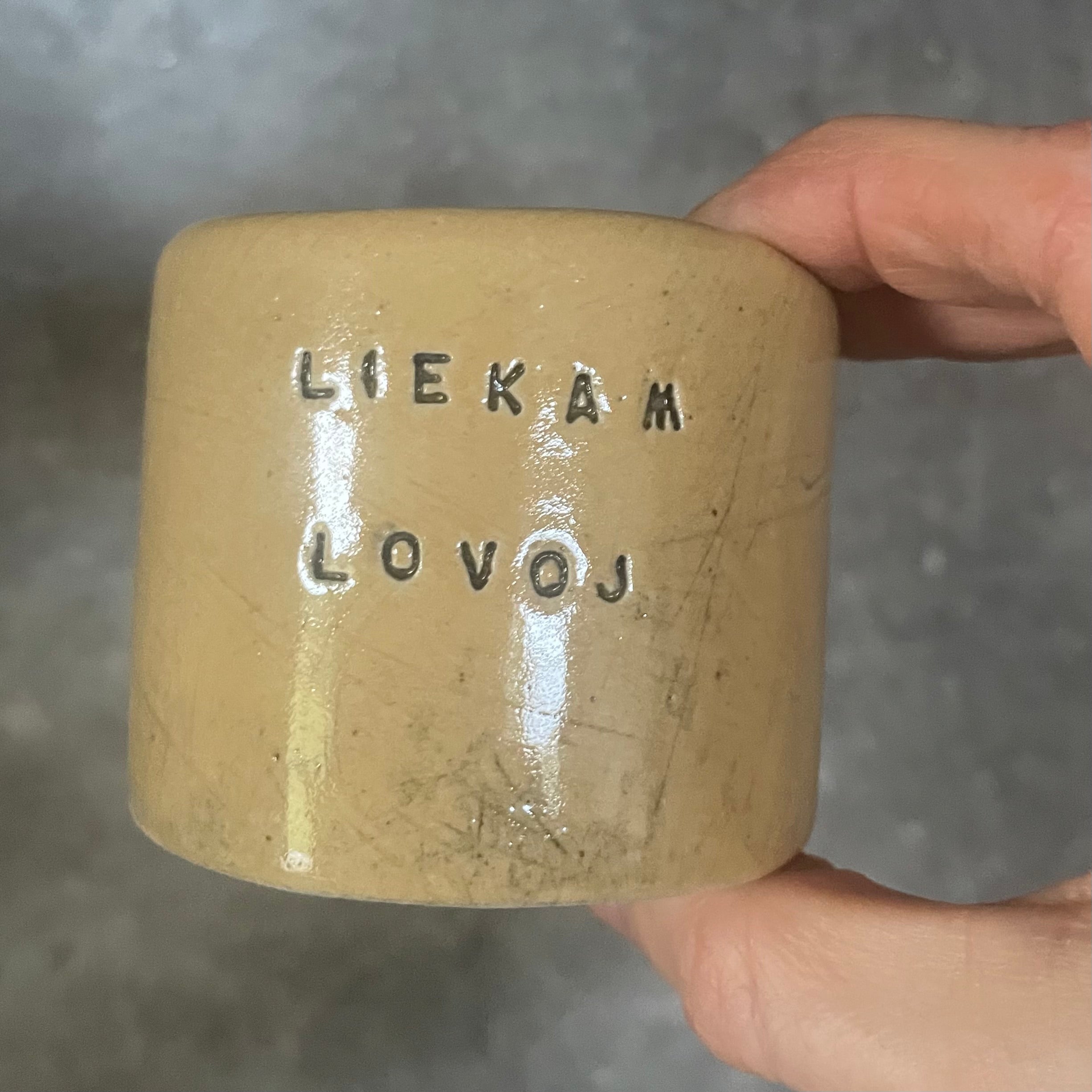 A pair of small mugs with words in Lithuanian