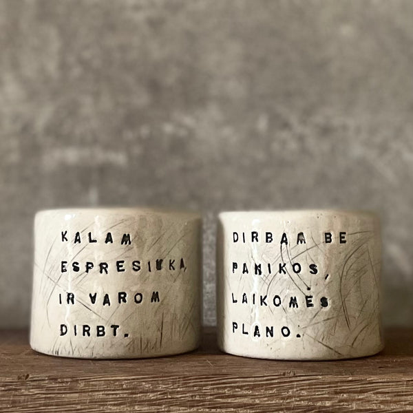A set of small mugs with words in Lithuanian