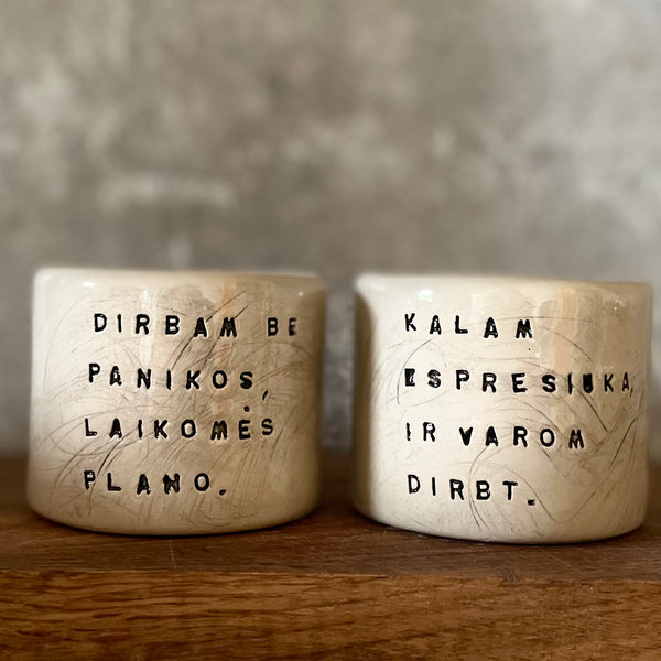 Du maži espresso puodeliai su tekstu apie darbą