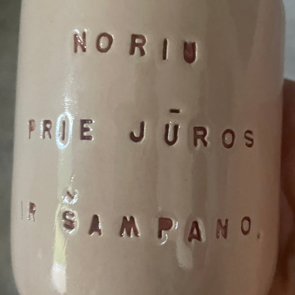 Small pink mug without handle with text in Lithuanian