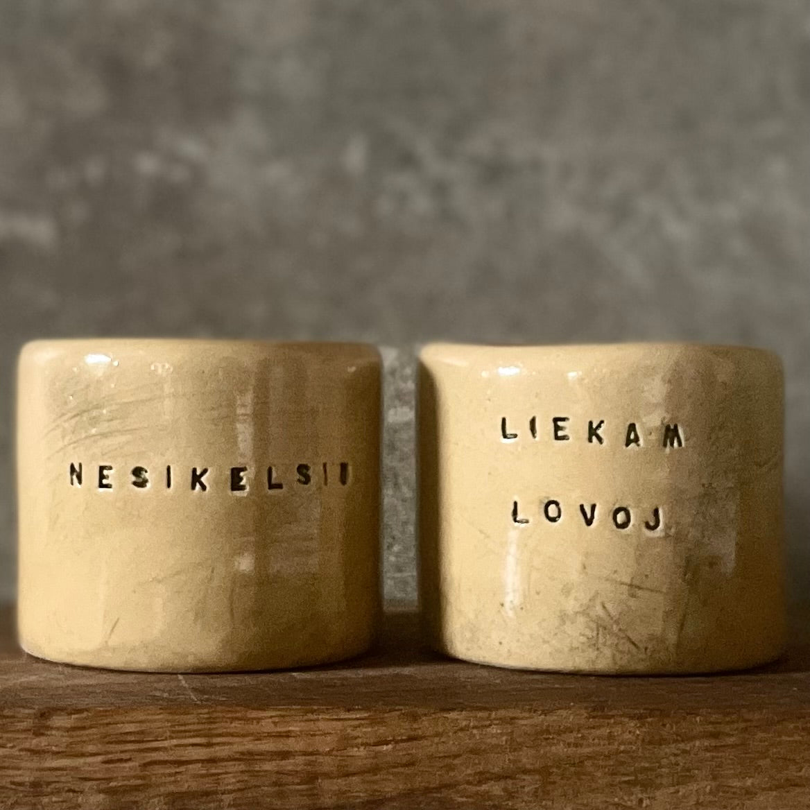 A pair of small mugs with words in Lithuanian