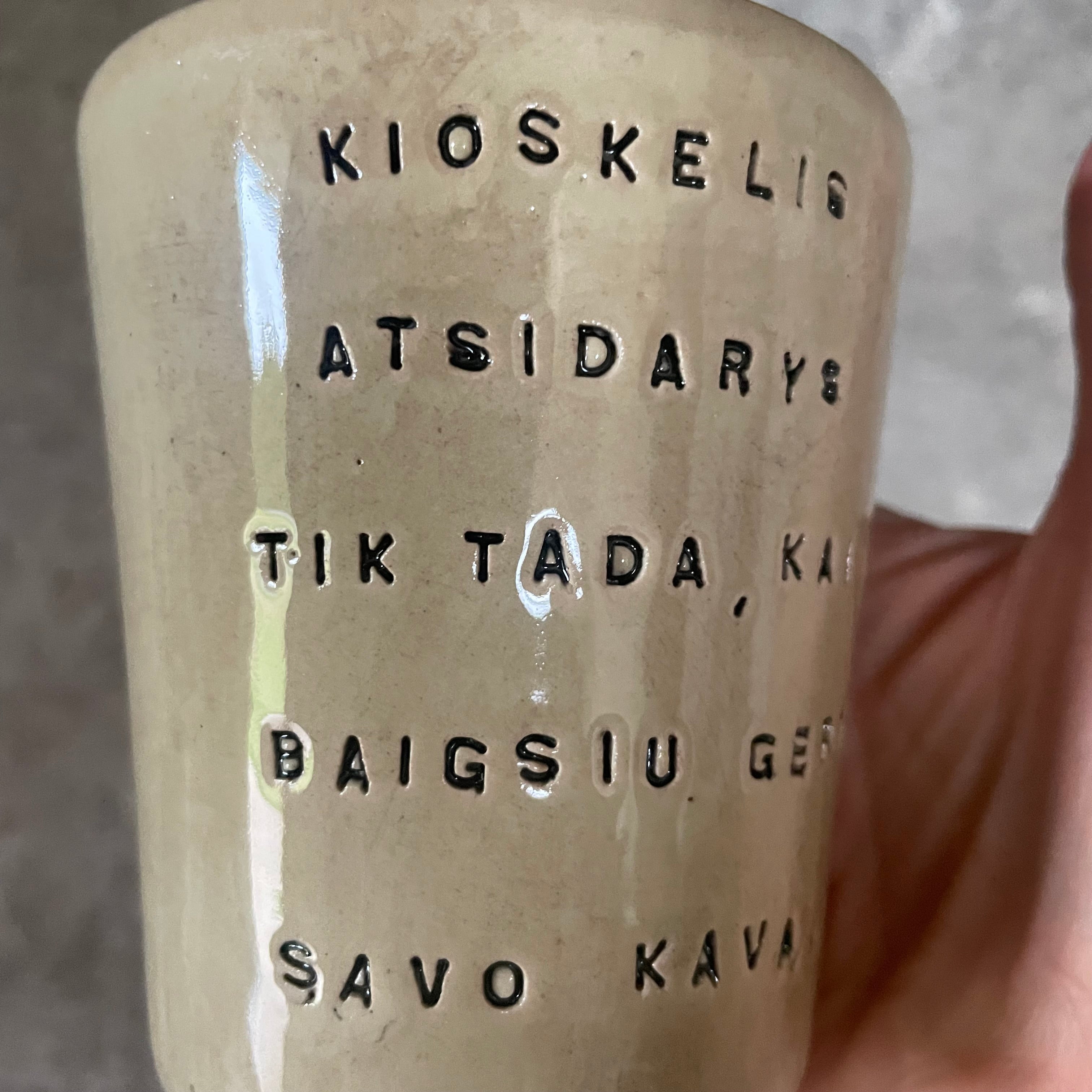 Puodelis su smagiu užrašu apie kavą ir kioskelį