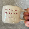 Puodelis su citata “No artist tolerates reality"