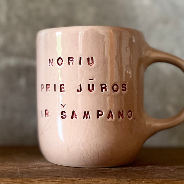 Puodelis su užrašu apie šampaną