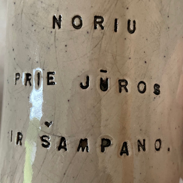 Taškuotas puodelis apie šampaną ir jūrą