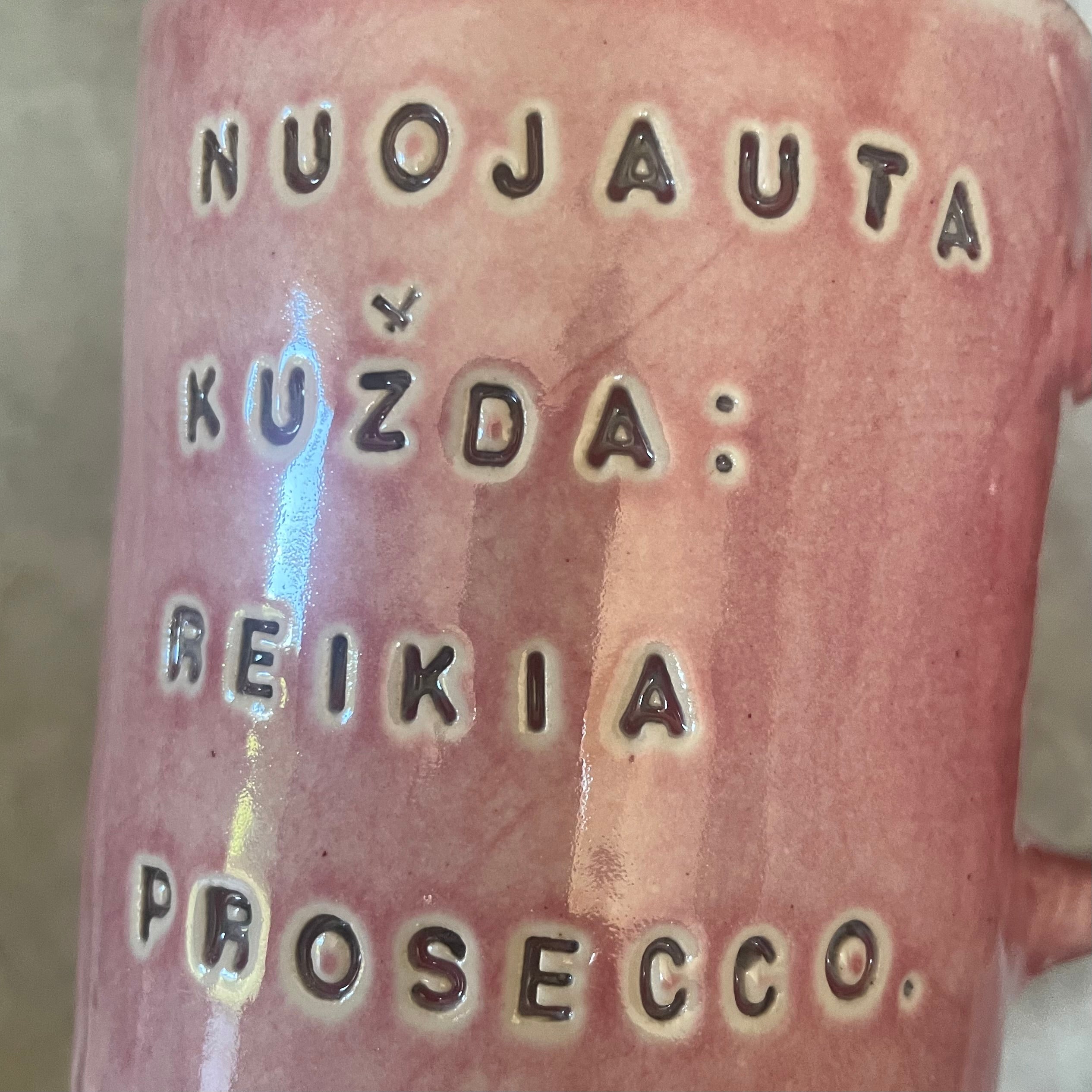 Puodelis su linksmu užrašu apie prosecco