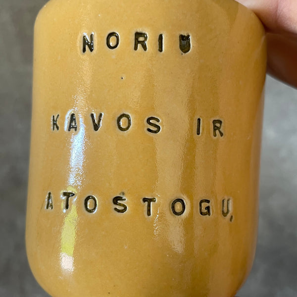 Geltonas mažas puodelis apie kavą ir atostogas