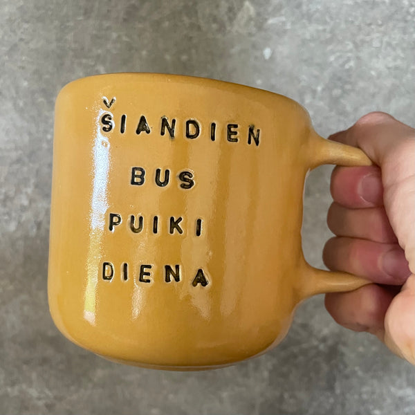 Large yellow mug with text in Lithuanian